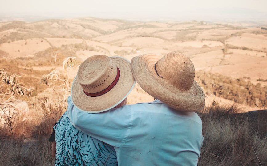 two person wearing sunhats sitting on rock
