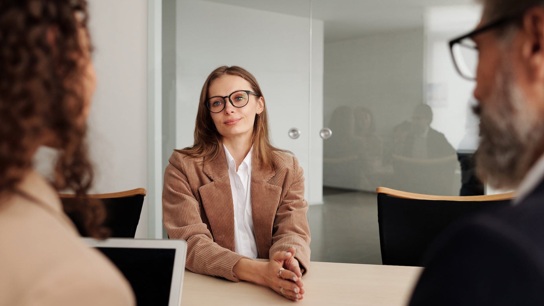 woman in brown blazer seated beside table