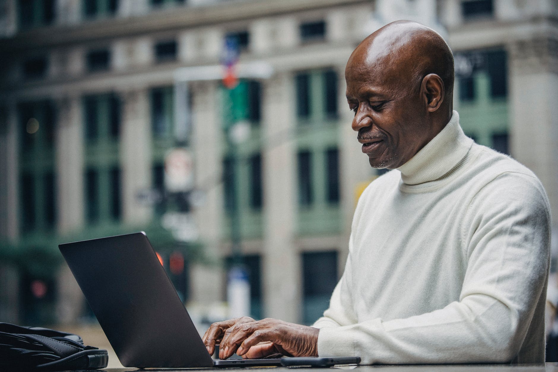 elegant middle aged ethnic male freelancer working on laptop in cafe