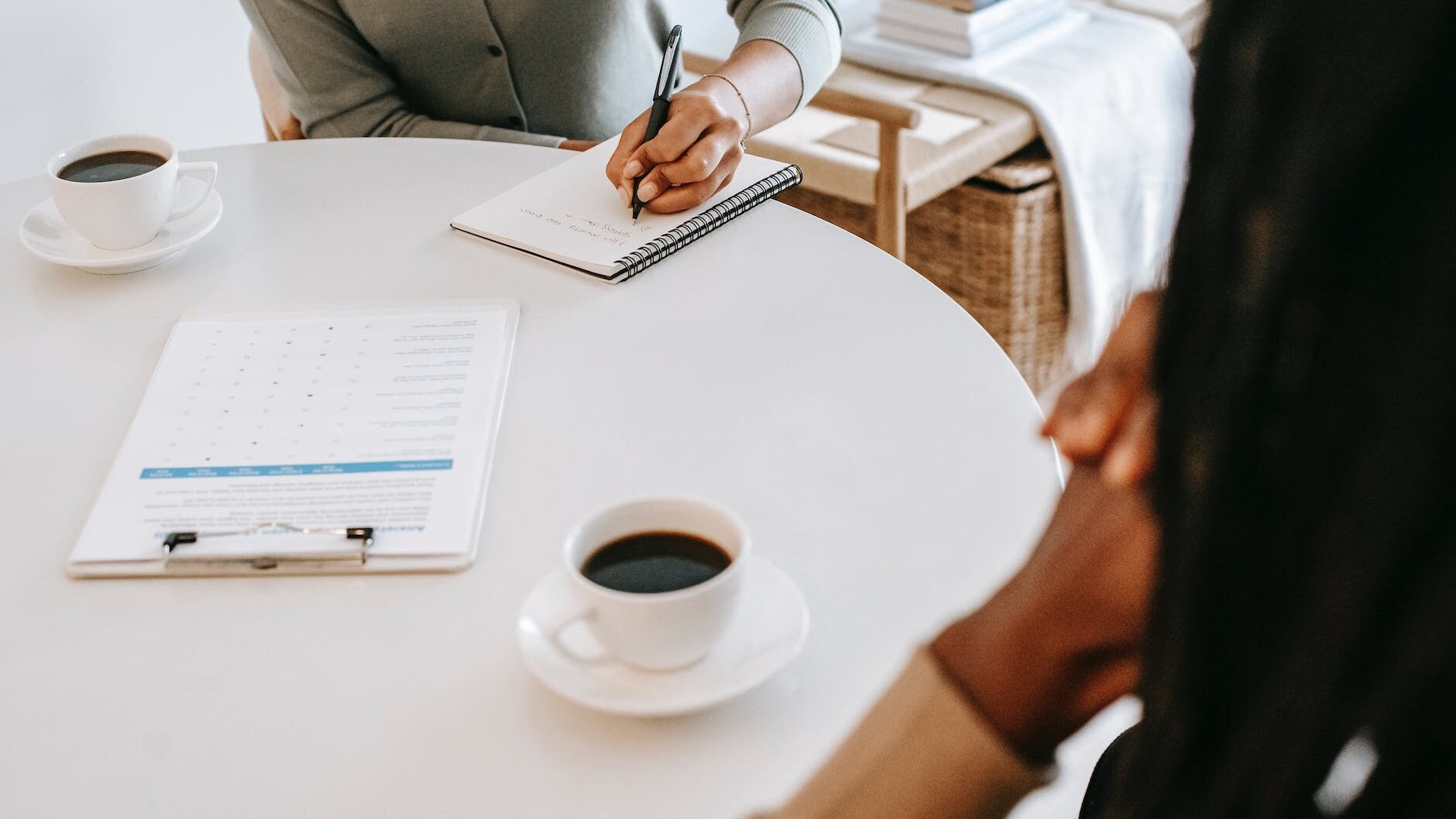 crop interviewer writing in notepad and talking to job seeker