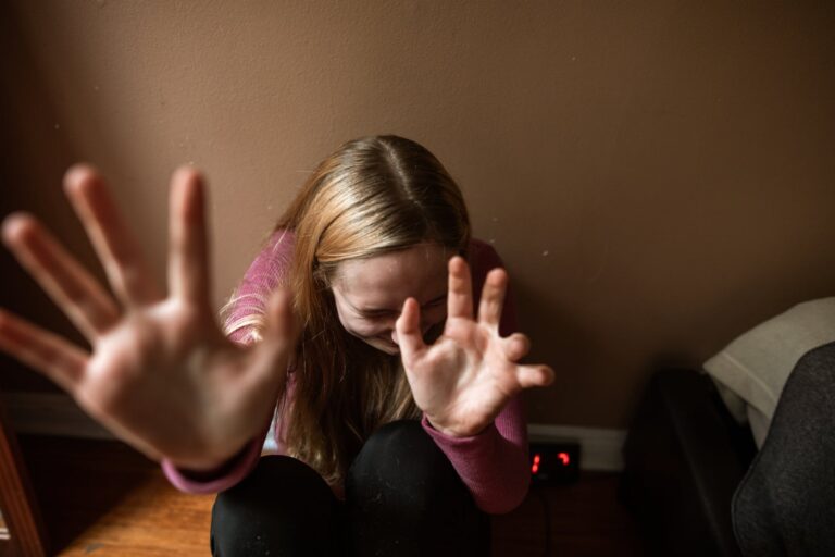 a woman in distress sitting in a corner