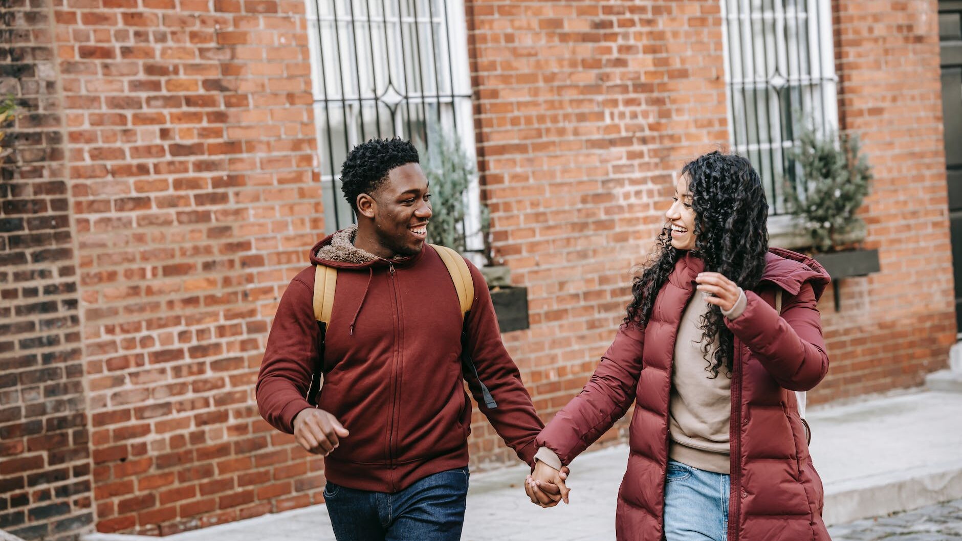 content multiracial couple holding hands while walking on urban pavement