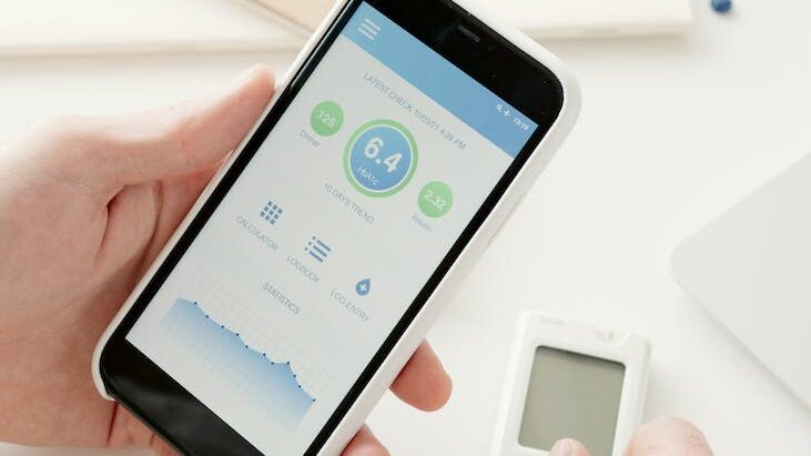 person holding smartphone with blood sugar level on screen