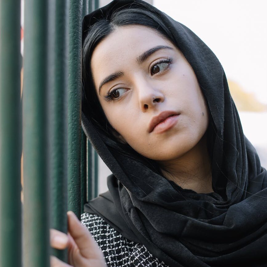 serious woman in headscarf near fence